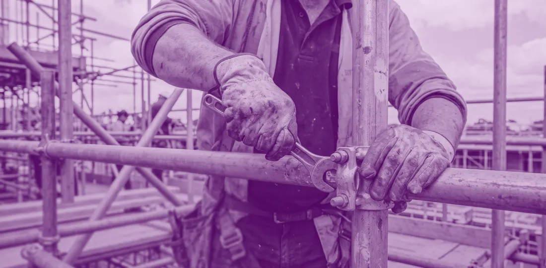 Worker erecting scaffolding on a construction site