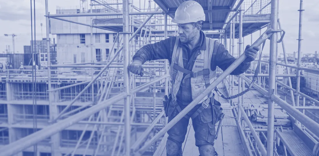 Worker erecting scaffolding on a construction site